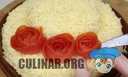 Сворачиваем полоску из кожуры помидора в рулон, получается цветочек. Выкладываем цветочки на салат.